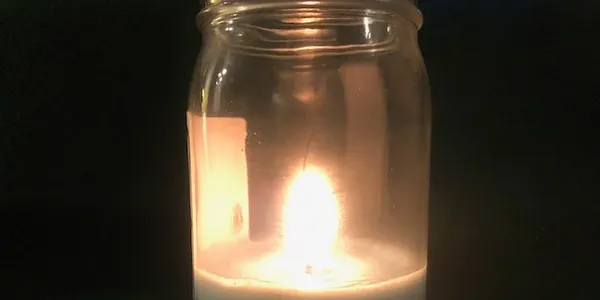 a candle lit in a mason jar